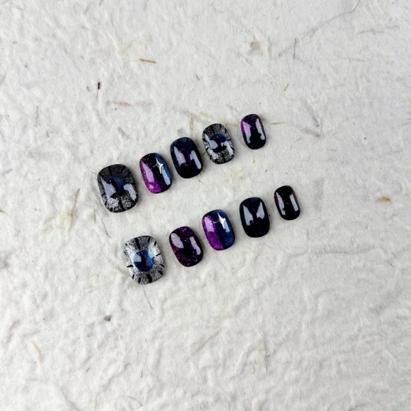Ongles à presser obliques courts mystérieux en dégradé noir violet avec des reflets chatoyants et oeil de chat, des faux ongles pour les fêtes ou une