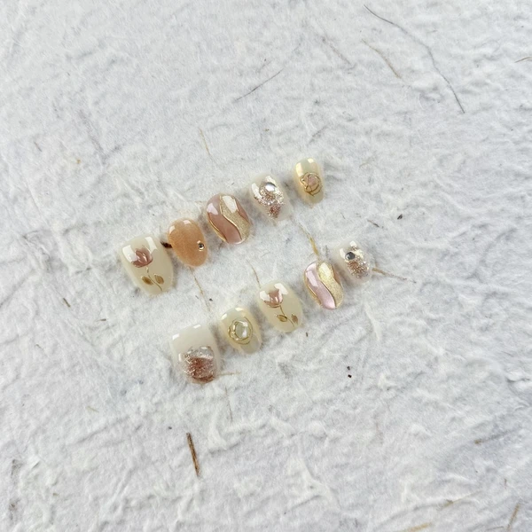 Ongles à presser ovales courts élégants en nude doux avec des lignes dorées et des strass. Parfait pour un usage quotidien et les occasions sociales