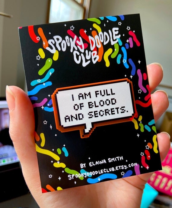 BLOOD & SECRETS Acrylic Glow Pin - Spooky Doodle Club (2 pouces)