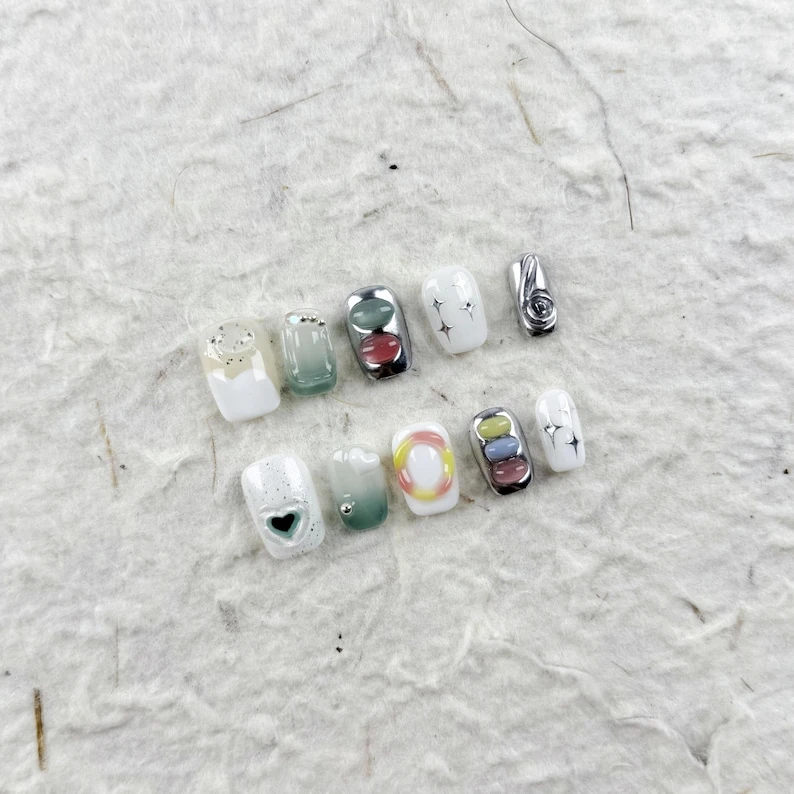 Presse-ongles carrés artistiques en blanc avec reflets argentés, dégradé de vert avec paillettes, incrustations de résine métallique et motifs