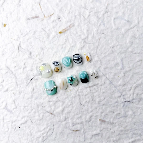 Courte pression ovale sur les ongles en bleu pastel avec des perles, des étoiles, des smileys et des images de chat, de jolis faux ongles pour les