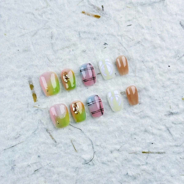 Charmant petit carré à presser sur les ongles en dégradé rose-vert avec des accents dorés et des motifs en quadrillage, parfait pour un mélange