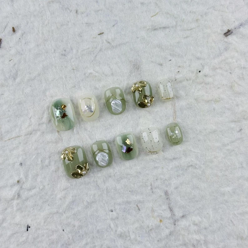 Presse-ongles carré court raffiné en beige doux, orné de feuilles et de lignes dorées, idéal pour les trajets quotidiens et les occasions spéciales