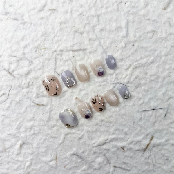 Charmants ongles courts carrés roses et violets, avec des paillettes argentées, des fleurs peintes à la main et une esthétique douce pour les