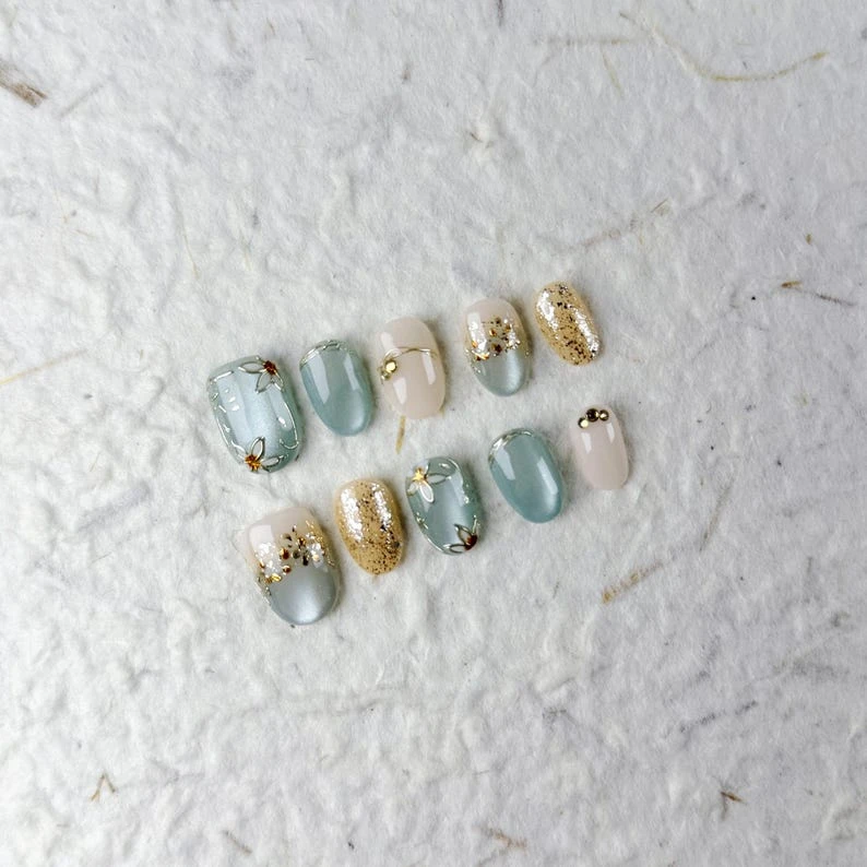Délicat court ovale à presser sur les ongles en bleu doux, beige et or avec des motifs floraux. Parfait pour un usage quotidien et des rassemblements