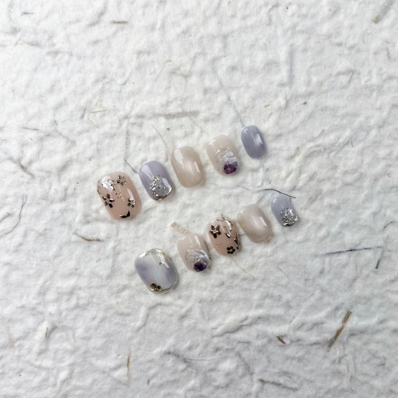 Charmants ongles courts carrés roses et violets, avec des paillettes argentées, des fleurs peintes à la main et une esthétique douce pour les