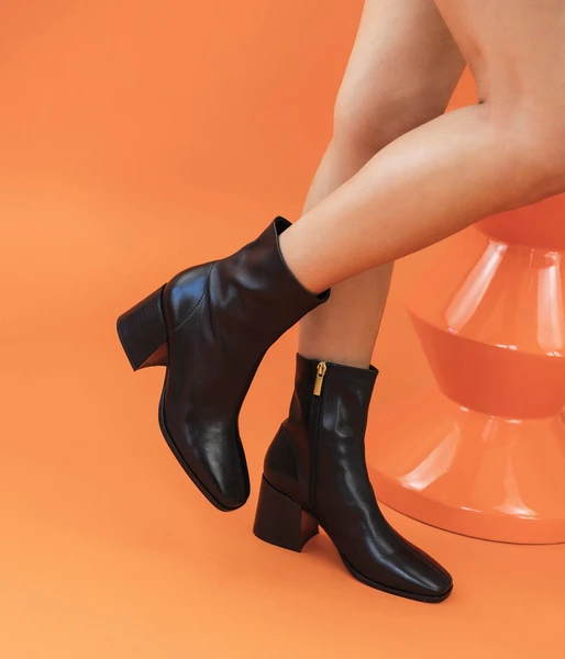 Un boot noir en cuir lisse au look à la fois sobre et audacieux inspiré du vestiaire des années 70