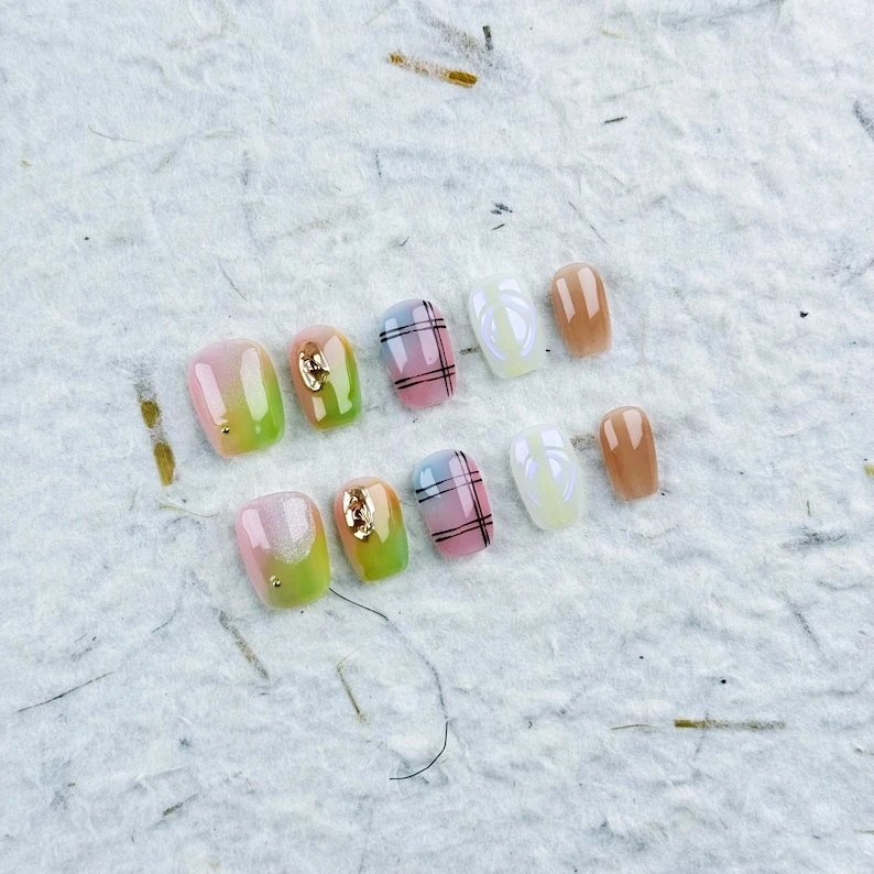 Charmant petit carré à presser sur les ongles en dégradé rose-vert avec des accents dorés et des motifs en quadrillage, parfait pour un mélange