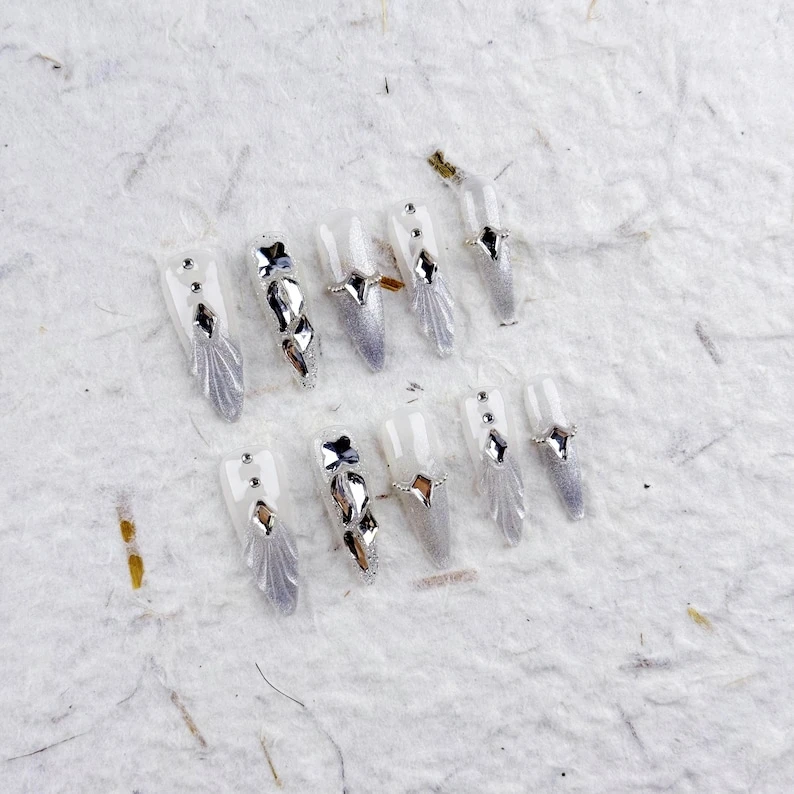 Ongles pressés style long élégant avec blanc translucide, paillettes argentées et formes géométriques 3D, faux ongles pour mariages et soirées glamour