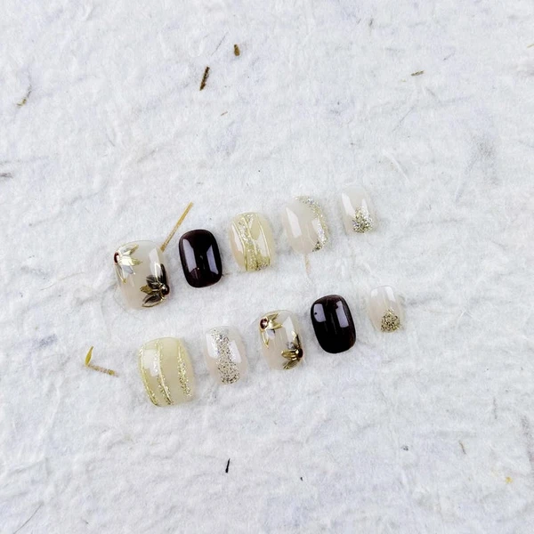 Presse carrée courte sur les ongles dans des tons clairs avec des motifs floraux dorés et des rayures, des faux ongles pour un usage quotidien et les